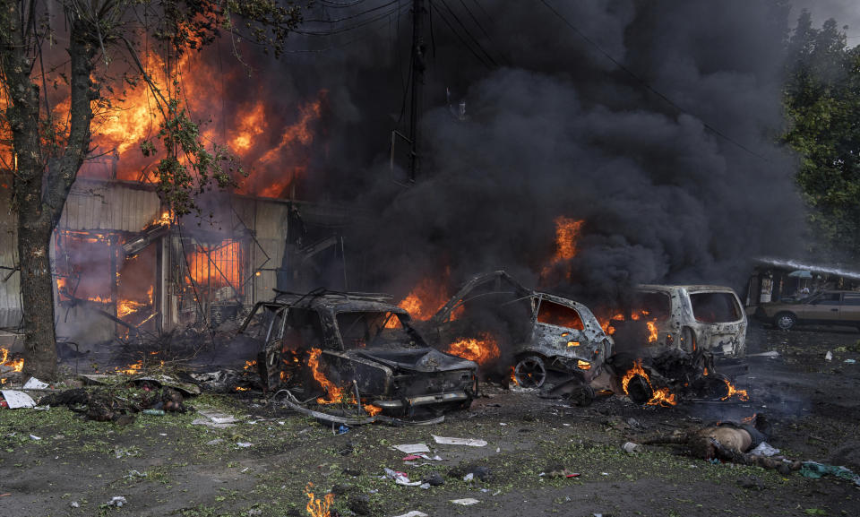 A dead body lies on the ground in front of a burning market after an attack in the city center of Kostiantynivka, Ukraine, Wednesday, Sept. 6, 2023. More than a dozen people were killed and dozens more were wounded Wednesday when shelling struck a market in the city in eastern Ukraine. (AP Photo/Evgeniy Maloletka)