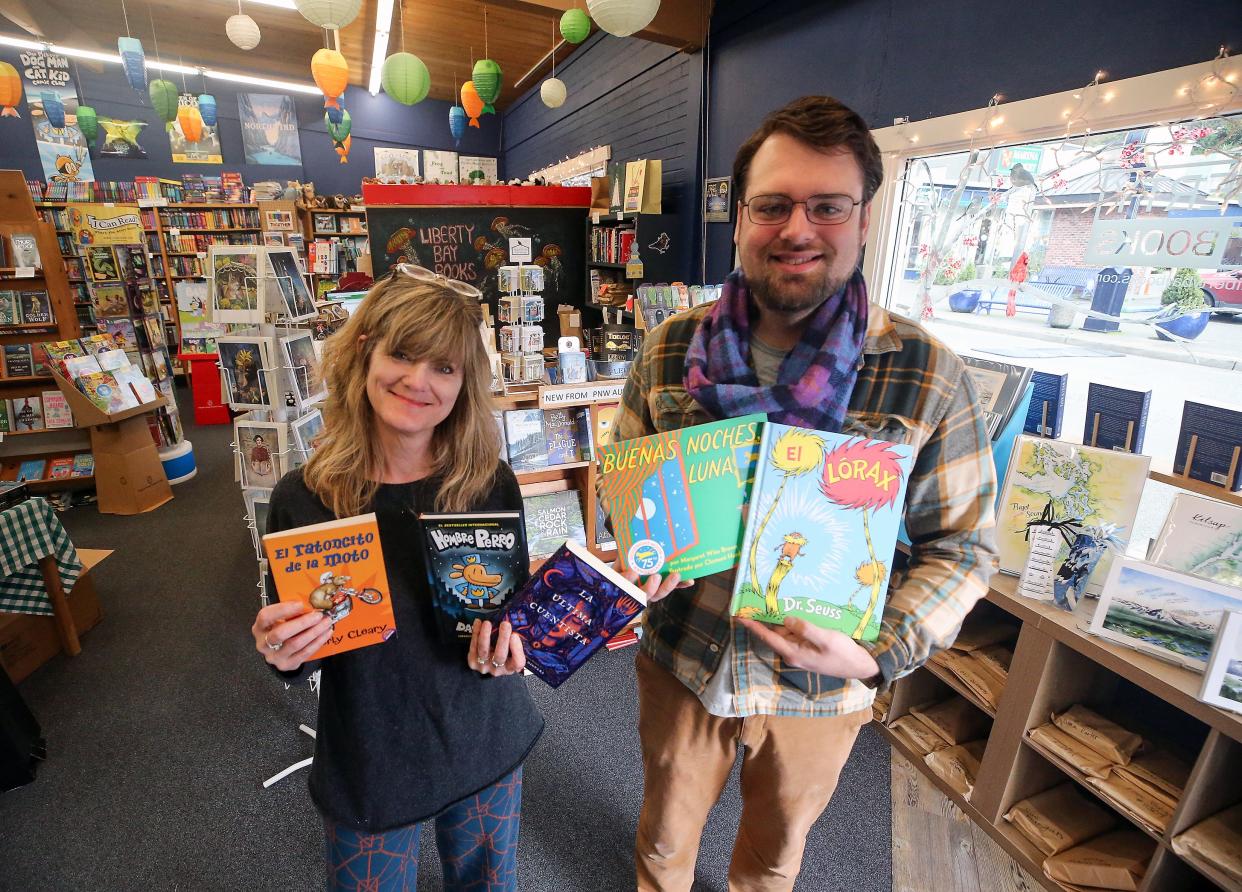 Suzanne Selfors and Walker Ranson of Liberty Bay Books hold a few books that they are donating to a KIAC project that gifts Spanish-language books to children in immigrant families.