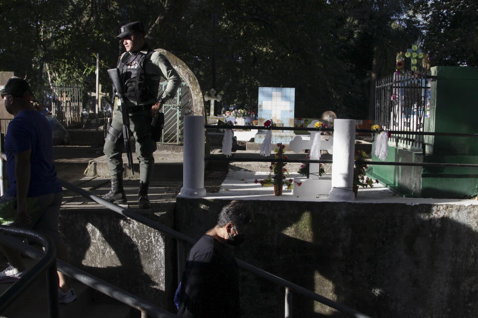 Un oficial de policía permanece de guardia en una de las áreas del Cementerio Nueva San Salvador, durante las celebraciones del Día de Muertos en Santa Tecla, El Salvador, el miércoles 2 de noviembre de 2022. El Salvador extendió su estrategia de persecución contra las pandillas y comenzó a destruir tumbas de sus integrantes, identificadas con distintivos propios de las bandas, en los cementerios públicos del país. (Foto AP/Salvador Meléndez)