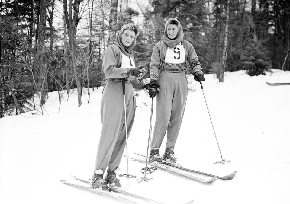 FILE - Rhona Wurtele, left, and her twin sister, Rhoda, right, both from Westmount, Quebec, and the Penguin Ski Club, look on after downhill and slalom National Championship races at Cannon Mountain in Franconia, N.H., March 3, 1946. Canadian Olympic ski racers Lucile Wheeler, 89, and Rhoda, 102, have been friends for nearly 80 years. (AP Photo/Abe Fox, File)