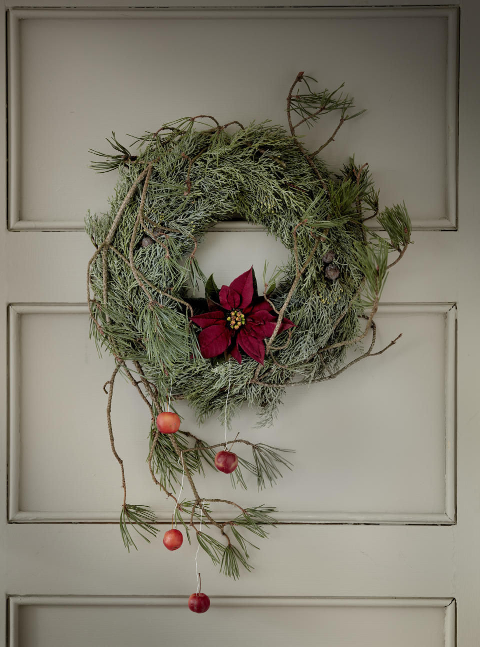 <p> Take a contemporary approach to even the most rustic wreath by adding an asymmetric element. Here, a branch decorated with crab apples brings a looser touch to the design. </p> <p> Christmas foliage – such as Cypress – forms the body of the wreath, with long pine branches wrapped over the top. A cut poinsettia inserted at the base of the circle adds a vivid hit of color and style. </p> <p> A cut poinsettia will last longer if, immediately after cutting, the stem is dipped into hot water for a few seconds, then plunged into cold water. Place the bloom into a flower tube filled with water, then insert this into your wreath. </p>