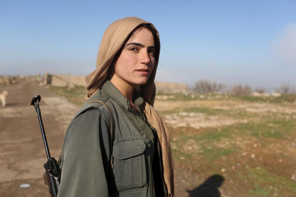 A female Kurdistan Workers Party (PKK) fighter stands near a security position in Sinjar, March 13, 2015. Women fighters at a PKK base on Mount Sinjar in northwest Iraq, just like their male counterparts, have to be ready for action at any time. Smoke from the front line, marking their battle against Islamic State, which launched an assault on northern Iraq last summer, is visible from the base. Many of the women have cut links with their families back home; the fighters come from all corners of the Kurdish region.