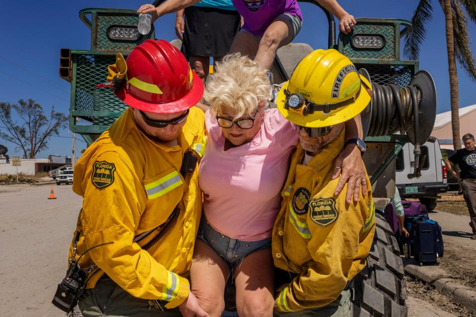 Diana Kauth is helped off a rescue rig by Florida Forest Service firefighters after riding out Hurricane Ian inside her neighbor’s two-story home in Fort Myers Beach, on San Carlos Island, on Friday, Sept. 30, 2022.