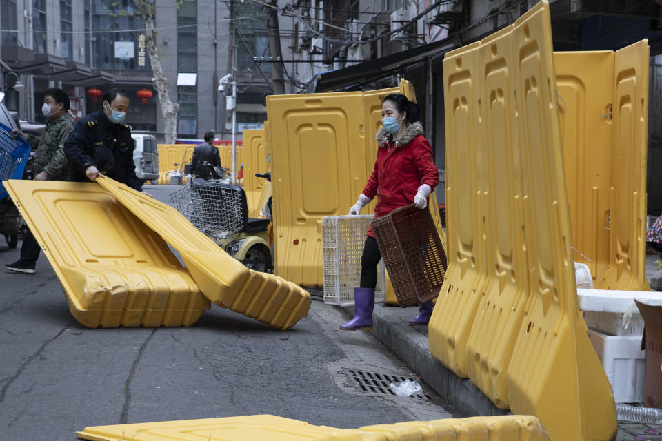 FILE - In this April 5, 2020, file photo, a city worker removes barriers used to seal off a community as the city of Wuhan slowly loosen up ahead of a lifting of the two month long lockdown in central China's Hubei province. One year after Wuhan’s lockdown to curb the coronavirus, the Chinese city has long since sprung back to life. (AP Photo/Ng Han Guan, File)