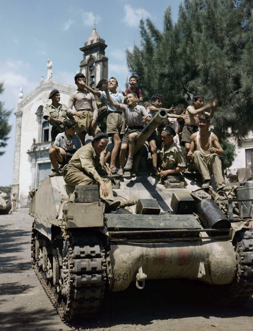 Local children climb aboard a Sherman tank