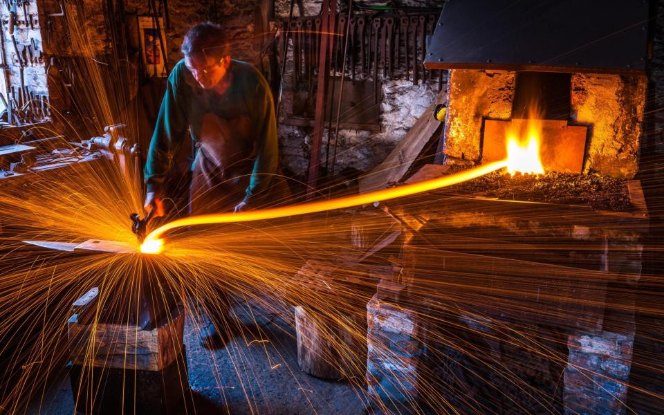 Hammer and tongs: a blacksmith at work at a forge in Malmesbury, Wiltshire - alamy