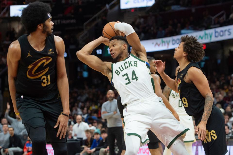 Milwaukee Bucks' Giannis Antetokounmpo (34) looks to pass between Cleveland Cavaliers' Jarrett Allen (31) and Craig Porter (9) during the second half of an NBA basketball game in Cleveland, Friday, Dec. 29, 2023. (AP Photo/Phil Long)