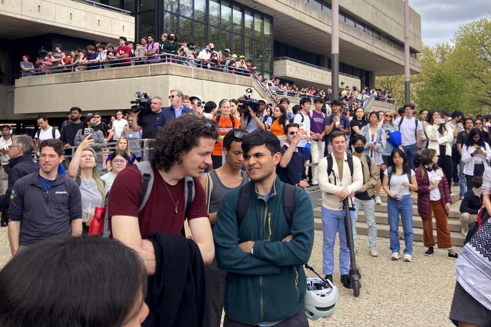 Students and passersby watch from a nearby building steps as Pro-Palestinian protestors gather outside a student encampment on the campus of the Massachusetts Institute of Technology, after a 2:30pm deadline passed to leave the encampment, Monday May 6, 2024, in Cambridge, Mass. (AP Photo/Steve LeBlanc)