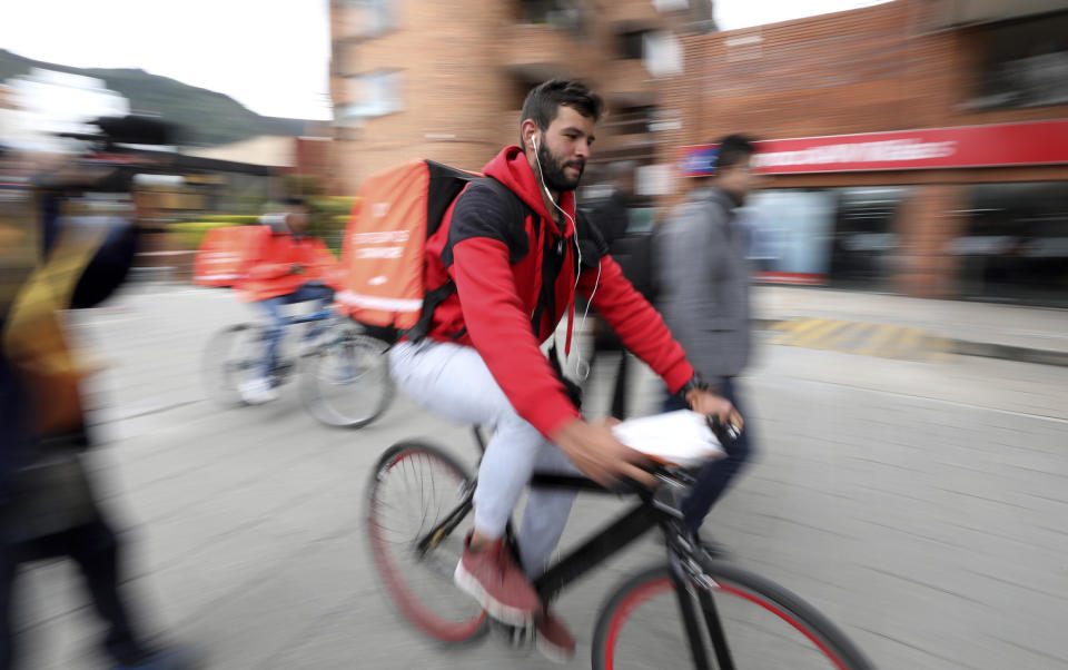 Venezuelan courier Samuel Romero, 21, takes an order to a Rappi customer on his bicycle in Bogota, Colombia, Tuesday, July 9, 2019. In a 15-hour workday Romero hopes to make around $15, the equivalent of Venezuela's monthly minimum wage but barely enough to get by in costlier Colombia. (AP Photo/Fernando Vergara)