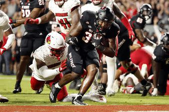 North Carolina State's Delbert Mimms III (34) breaks the tackle of Louisville's Stanquan Clark, left, during the first half of an NCAA college football game in Raleigh, N.C., Friday, Sept. 29, 2023. (AP Photo/Karl B DeBlaker)