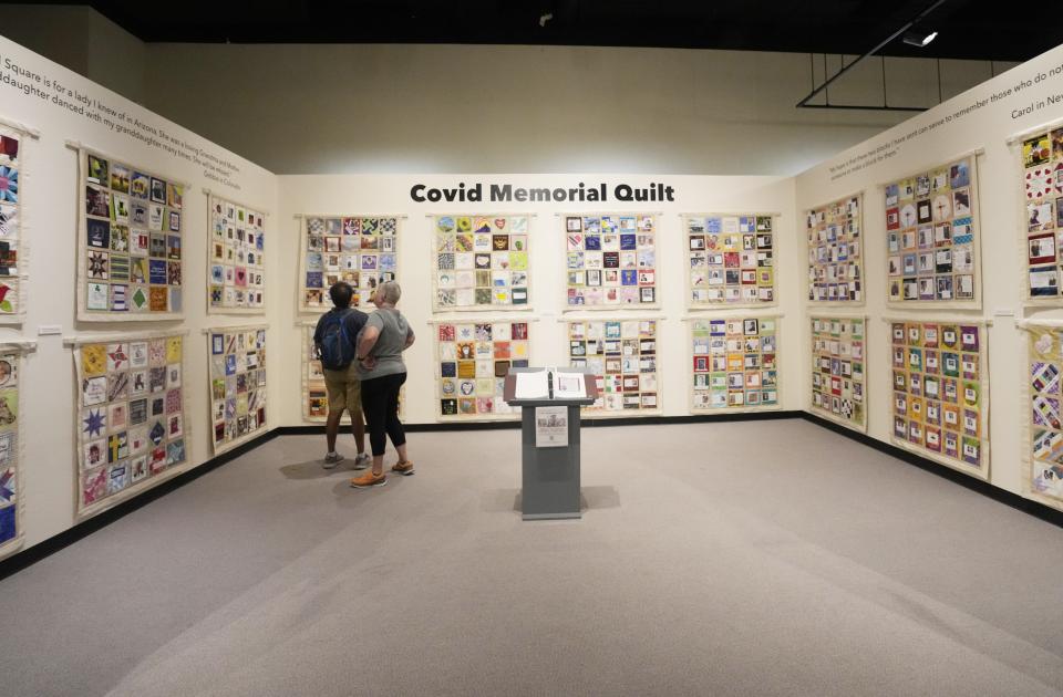 Visitors look at a COVID Memorial Quilt on display during a COVID-19 memorial event at the Arizona Heritage Center on March 6, 2023.