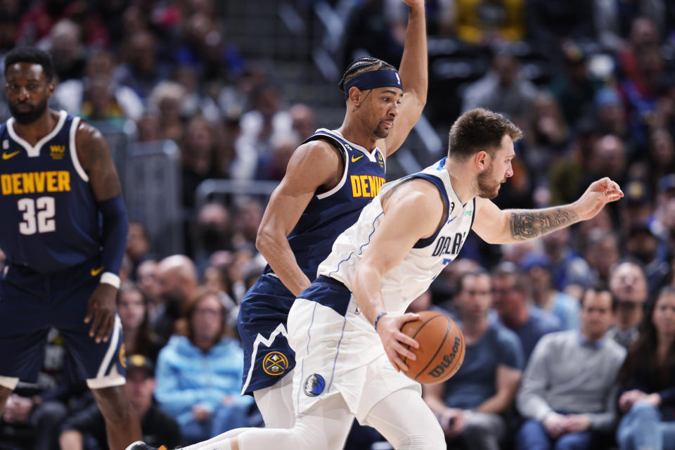 Dallas Mavericks guard Luka Doncic, front, drives as Denver Nuggets forward Zeke Nnaji defends during the second half of an NBA basketball game Tuesday, Dec. 6, 2022, in Denver. (AP Photo/David Zalubowski)