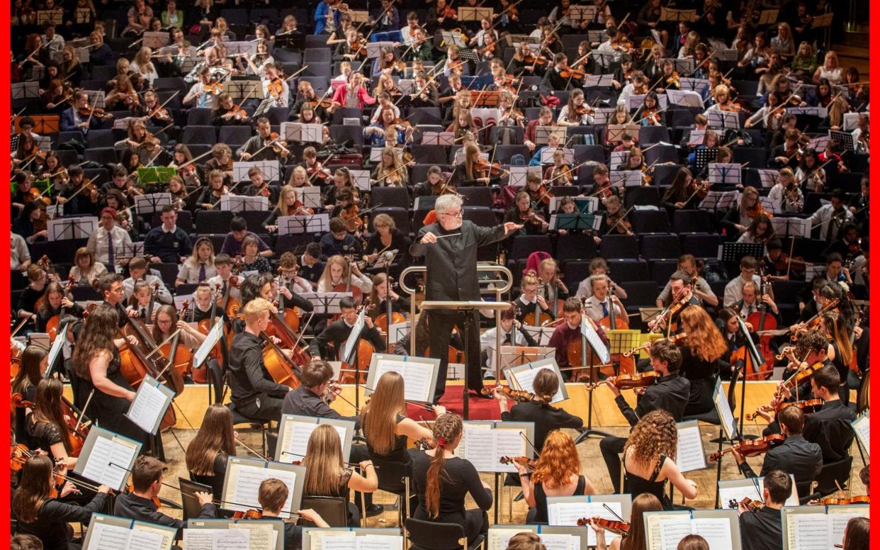 Sir James MacMillan conducts around 1200 school pupils in one of the largest orchestras ever assembled in Scotland, during a special concert at the 'Play to Learn' event at the Glasgow Royal Concert Hall, in June 2019 - PA