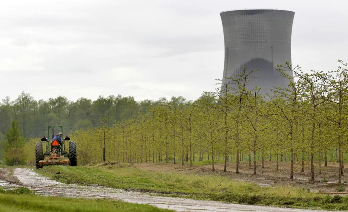 FILE - In this May 18, 2011, file photo, a worker drives a tractor through a tree farm in North Perry, Ohio, near the cooling towers of the Perry Nuclear Power Plant. A $60 million bribery case, involving ex-Ohio House Speaker Larry Householder and others, alleges to have helped prop up the Perry and Davis-Besse Nuclear Power Station in Oak Harbor, Ohio. The 2020 arrests of Householder and four associates in connection with the scheme have rocked politics and business across Ohio. (AP Photo/Amy Sancetta, File)