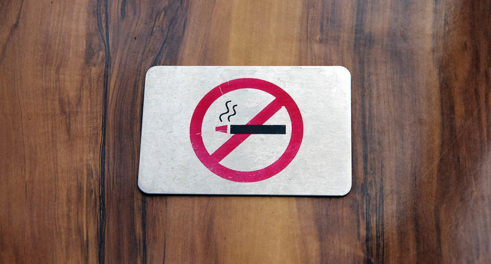 A wooden table with a no smoking sign on it.