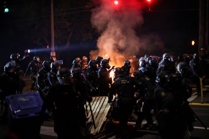 Police advance on protesters to clear a street on the 100th consecutive night of protests against police violence and racial inequality, in Portland, Oregon