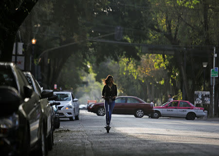 A woman uses an electric scooter in a neighbourhood in Mexico City, Mexico January 10, 2019. REUTERS/Daniel Becerril