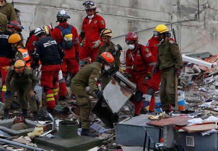 Israeli rescue team (in green) search for survivors in the rubble of a collapsed building after an earthquake in Mexico City, Mexico September 22, 2017. REUTERS/Henry Romero