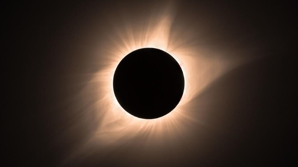     A black sphere with a crown-like pattern of orange lines radiating out in a circular pattern. 