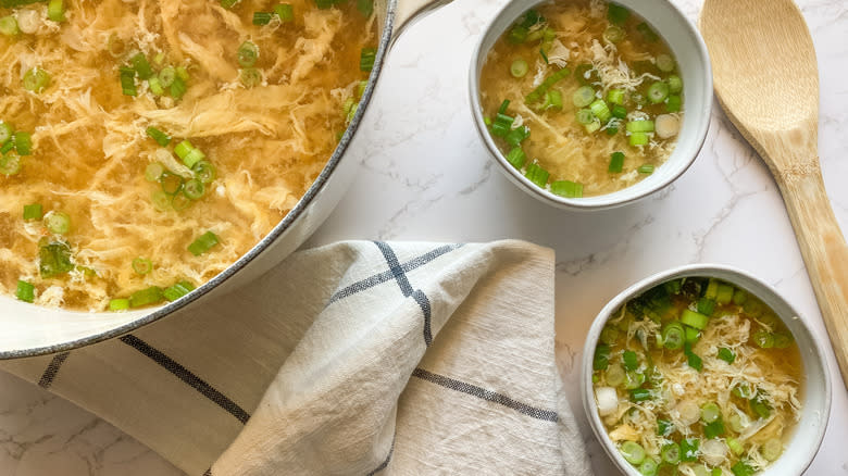 Top-down view of three bowls of egg drop soup garnished with scallions