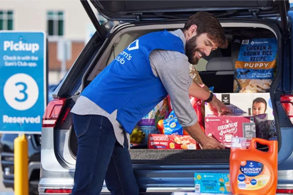 Sam's Club employee putting groceries in trunk of a customer's car at curbside pickup.