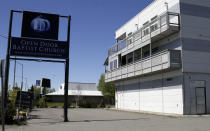 This May 24, 2021, photo shows the sign for the Open Door Baptist Church, which is located in a former strip club on the main floor of the building to the right with a sex shop located in the building across the street. Pastor Kenny Menendez hopes that the church — which is also situated between a marijuana retail store and downtrodden motels — could be a start to improving the neighborhood. (AP Photo/Mark Thiessen)