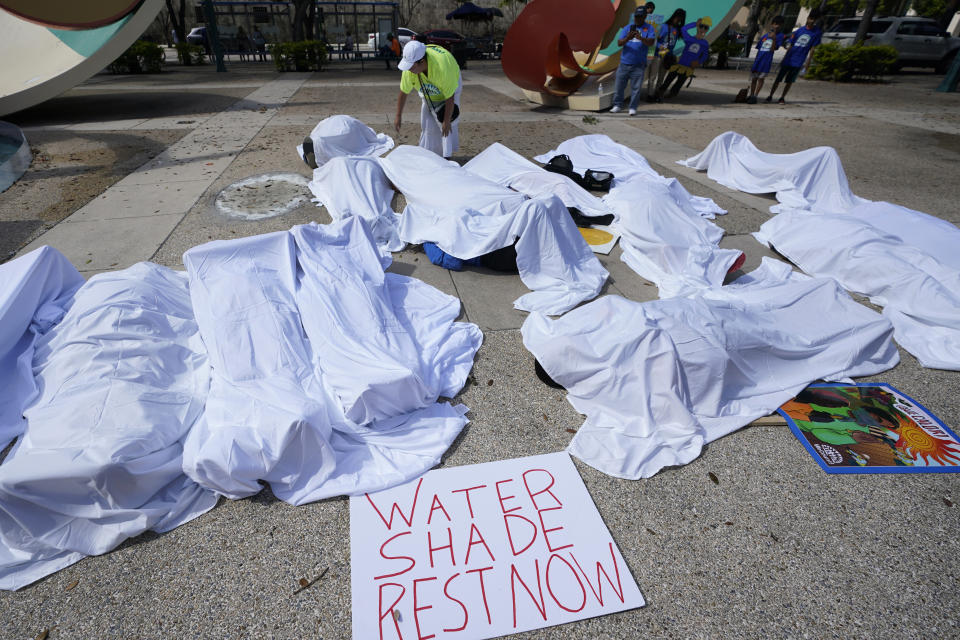 FILE - Demonstrators cover themselves with sheets to simulate workers killed by extreme heat, June 21, 2023, during a rally by outdoor workers demanding workplace protections against extreme heat, at the Stephen P. Clark Government Center in Miami. (AP Photo/Wilfredo Lee, File)