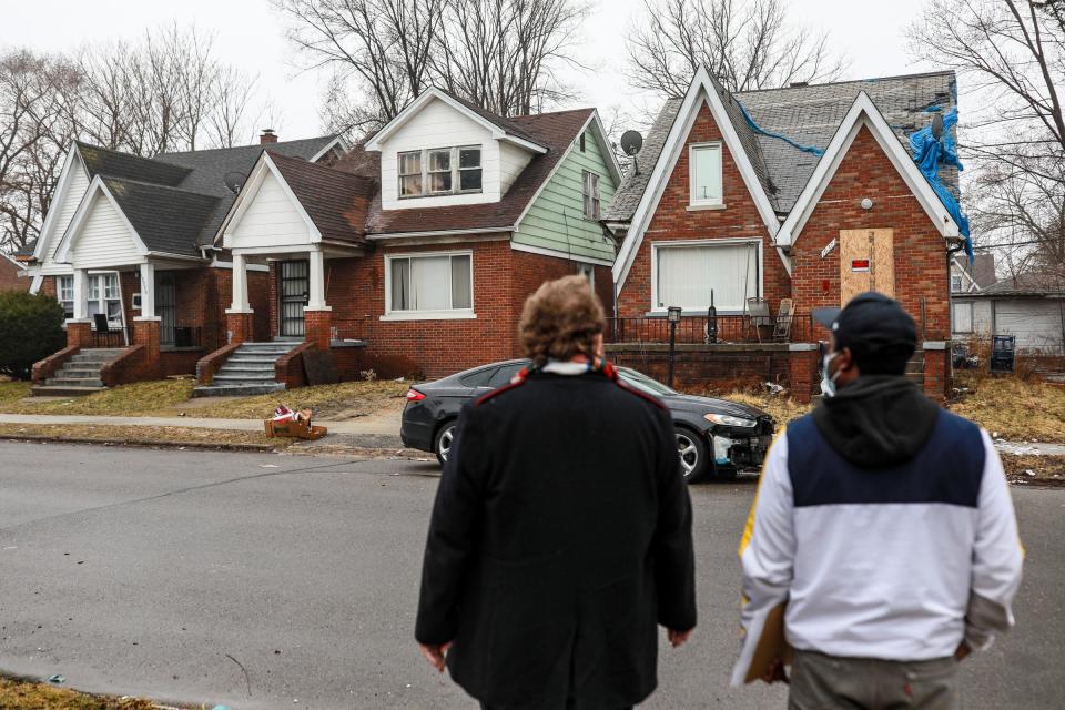 Eastside Community Network (ECN) Director of Sustainable Housing Ian McCain, 28, of Eastpointe, left, and Volunteer Willie Morgan, of Oak Park, right, walk up to what looks like an abandoned home to drop off a packet of information to help them save their home from property tax foreclosure on March 19, 2022. Property tax foreclosures are resuming in Wayne County after March 31. There's been a moratorium on occupied homes for the past two years. Nonprofit groups like ECN are working with the Wayne County Treasurer's Office to locate those homes marked for foreclosure.