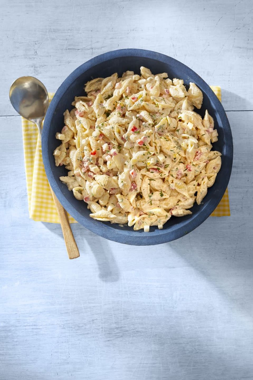 garden pasta salad in blue bowl with yellow napkin