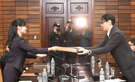 South Korean singer and chief delegate Yun Sang exchanges documents with Hyon Song Wol, head of the Samjiyon Orchestra, during their meeting at the truce village of Panmunjom, North Korea, March 20, 2018. The Unification Ministry/Yonhap via REUTERS