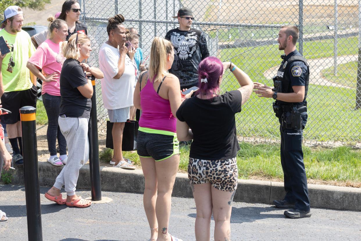 A Massillon police officer shares information with concerned Washington High parents outside Paul Brown Tiger Stadium where their children were gathered after a bomb threat earlier this school year.