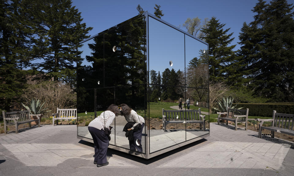 A woman peers into the sculpture "Infiniti Mirrored Room - Illusion Inside the Heart" by Japanese artist Yayoi Kusama at the New York Botanical Garden, Thursday, April 8, 2021 in the Bronx borough of New York. The expansive exhibit has opened, and ticket sales have been brisk in a pandemic-weary city hungry for more outdoor cultural events. (AP Photo/Mark Lennihan)