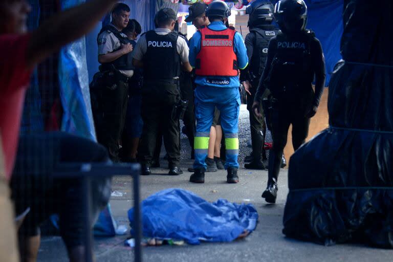 Agentes de policía y equipos de emergencia trabajan junto a un cuerpo en la escena de un crimen en un mercado popular del centro de Guayaquil el 3 de junio de 2024