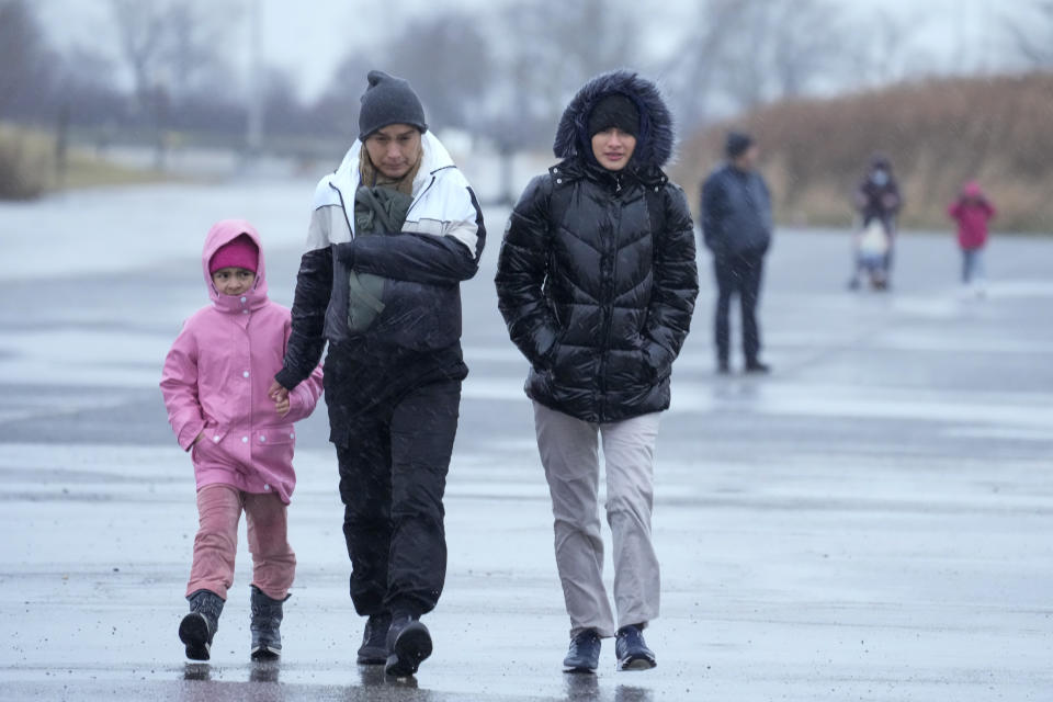 Immigrants run in the rain towards the tents at migrant housing location at Floyd Bennett Field, Tuesday, Jan. 9, 2024, in New York. New York City will evacuate the nearly 2000 immigrants housed in tents at the site due to an impending storm. (AP Photo/Mary Altaffer)