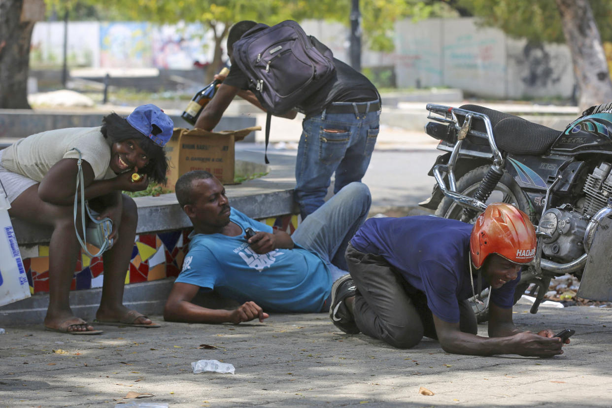 People take cover from gunfire during clashes between police and gangs near the National Palace in Port-au-Prince  on April 8, 2024.  (Odelyn Joseph / AP)