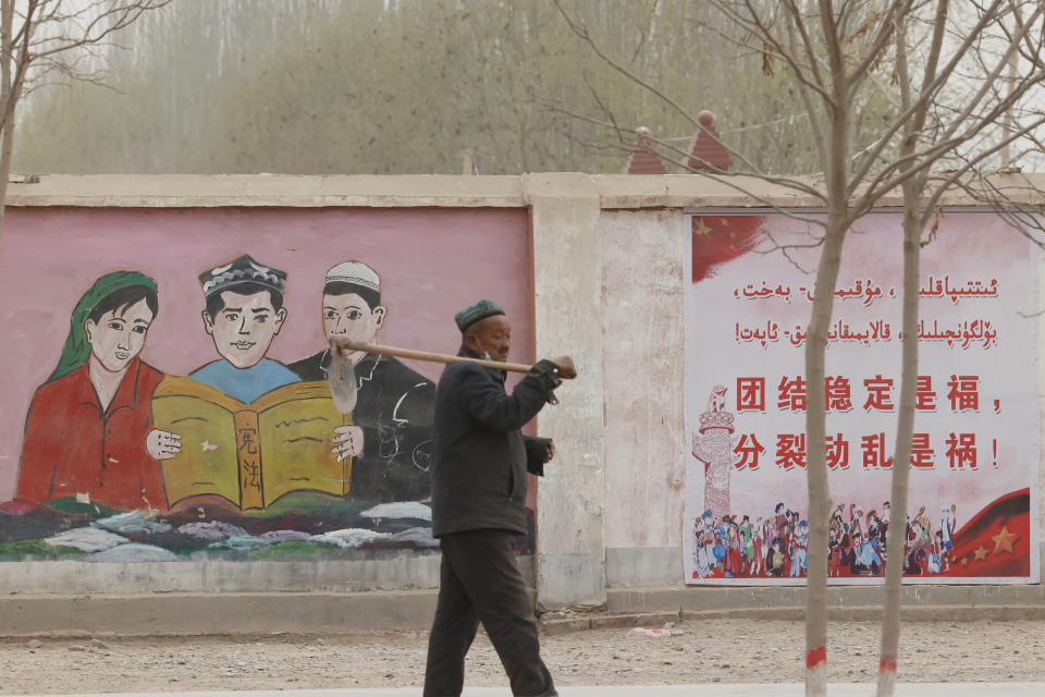 A farmer walks past government propaganda depicting ethnic minority residents reading the constitution with slogans which reads, "Unity Stability is fortune, Separatism and Turmoil is misfortune," near Kashgar in northwestern China's Xinjiang Uyghur Autonomous Region on March 19, 2021. Four years after Beijing's brutal crackdown on largely Muslim minorities native to Xinjiang, Chinese authorities are dialing back the region's high-tech police state and stepping up tourism. But even as a sense of normality returns, fear remains, hidden but pervasive. (AP Photo/Ng Han Guan)