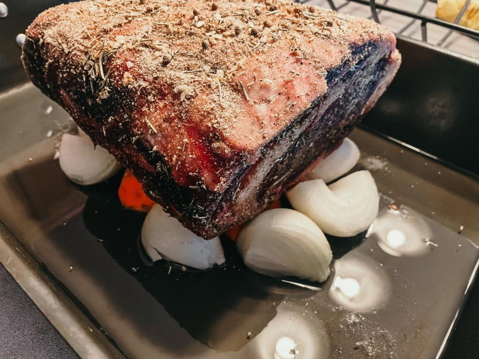 rib roast sitting on a bed of onions and carrots in a pan