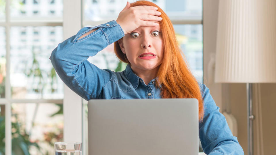 Shocked stressed young woman looking at laptop screen