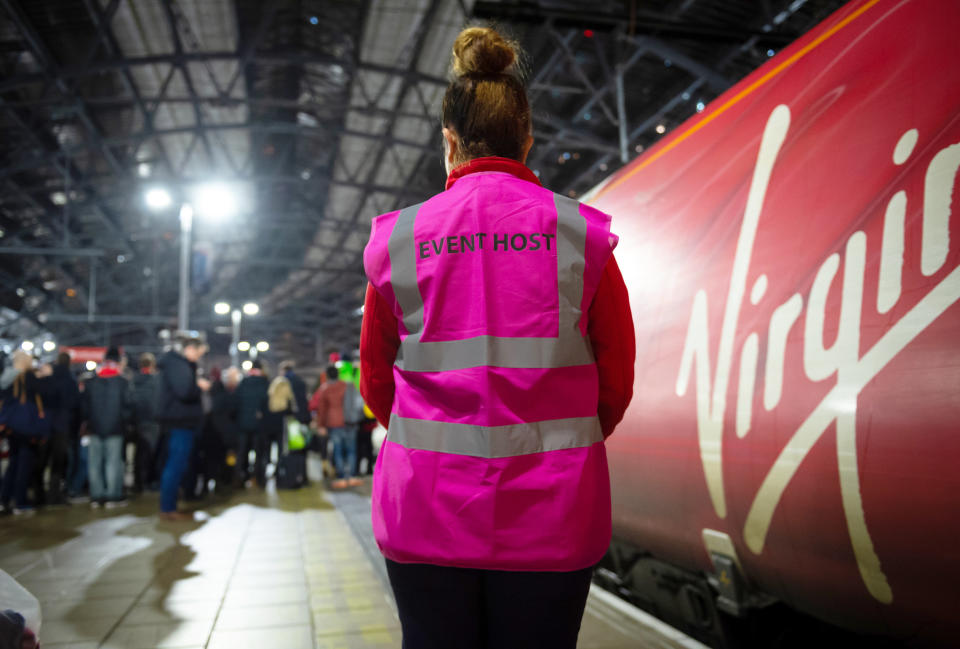 A woman stands next to a Virgin-branded train in the U.K.