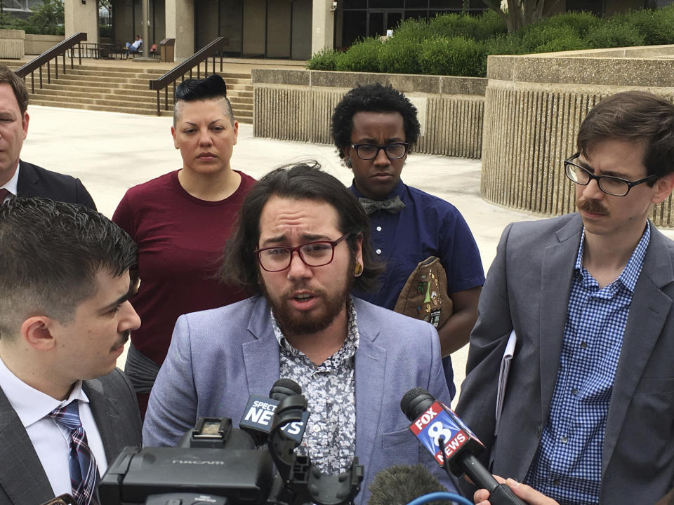 FILE - In a June 25, 2018 file photo, plaintiff Joaquin Carcano, center, addresses reporters after a hearing in Winston-Salem, N.C., on their lawsuit challenging the law that replaced North Carolina's "bathroom bill." A federal judge approved a legal settlement Tuesday, July 23, 2019 affirming transgender people’s right to use restrooms matching their gender identity in many North Carolina public buildings.(AP Photo/Jonathan Drew, File)