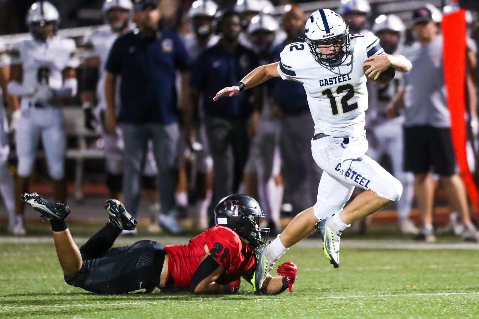 Casteel quarterback Landon Jury (12), right, skips past Williams Field outside linebacker Isaac Anderson (21), left, as they trail against Williams Field on Friday, September, 16, 2022, in Gilbert. The Casteel Colts won the game 23 to 20.
