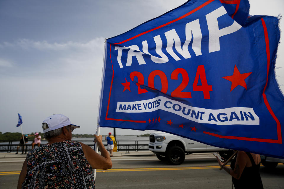 A supporter of former President Donald Trump holds a banner saying: Trump 2024, Make Votes Count Again.