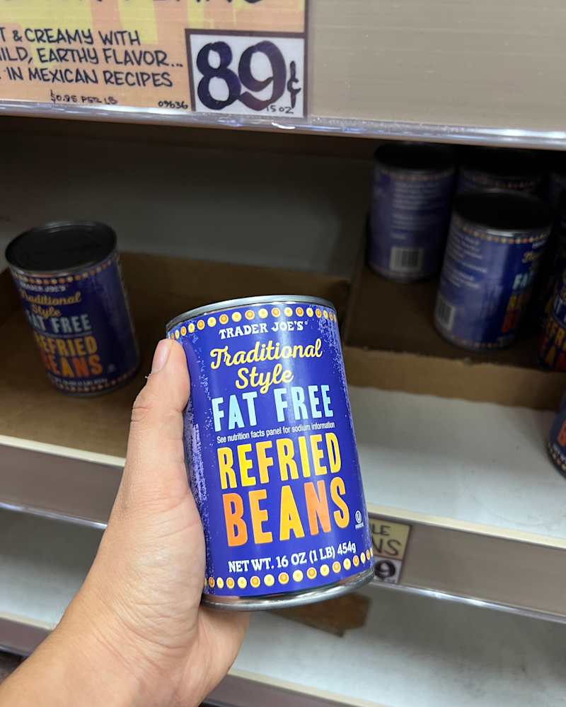 Someone holding can of Trader Joe's refried beans.