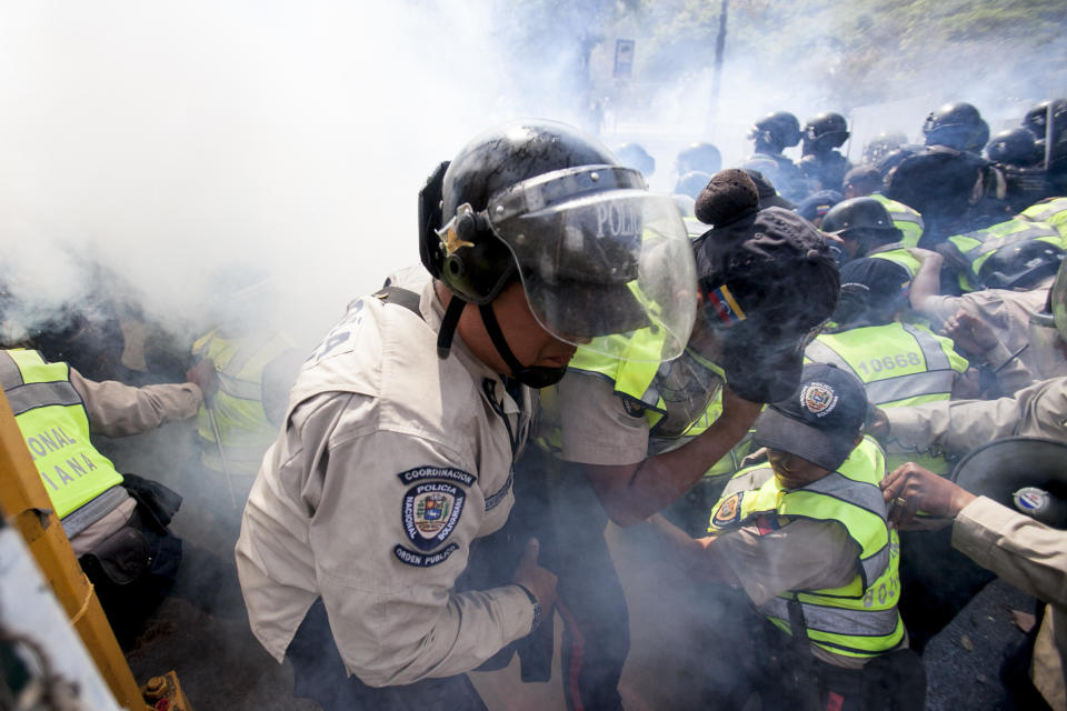 A Bolivarian National Police officer is removed from the front line after being affected by tear gas during clashes at a antigovernment protests in Caracas, Venezuela, Wednesday, March 12, 2014. According to local authorites, several deaths have been reported and a number of others, including three National Guardsmen, have been wounded after being shot by unknown assailants in two separate incidents in the central Venezuelan city of Valencia. (AP Photo/Alejandro Cegarra)