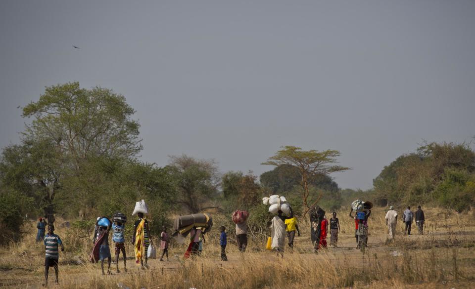 In this photo taken Thursday, Jan. 2, 2014, displaced people walk to find an unoccupied patch of ground where they can rest after arriving by river barge from Bor, some of the thousands who fled the recent fighting between government and rebel forces in Bor by boat across the White Nile, in the town of Awerial, South Sudan. (AP Photo/Ben Curtis)