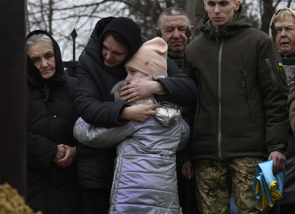 A woman and child embrace amid others gathered for the funeral service.