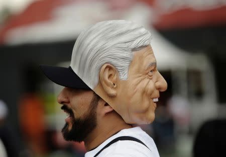 A supporter of Mexican presidential candidate Andres Manuel Lopez Obrador wears a mask resembling Lopez Obrador, while arriving at the country's largest soccer stadium for his closing campaign rally, in Mexico City, Mexico June 27, 2018. REUTERS/Daniel Becerril