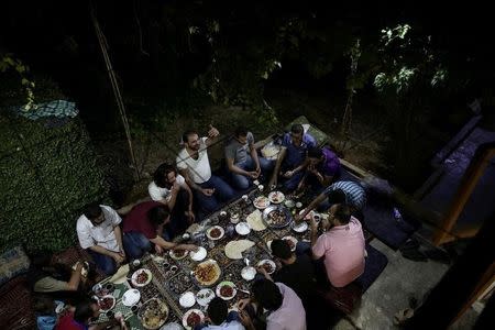 Crew of a film directed by Humam Husari (raising his hand) gather on a table after the end of filming in the rebel-held besieged town of Zamalka, in the rebel held Douma neighbourhood of Damascus, Syria October 6, 2016.REUTERS/Bassam Khabieh