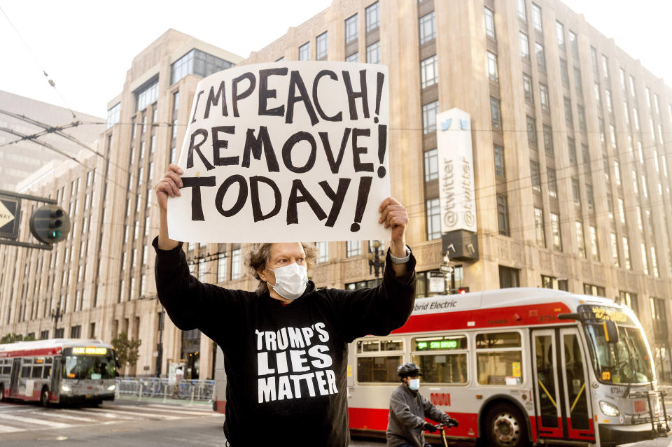 Kenneth Lundgreen holds a sign against President Donald Trump outside of Twitter headquarters on Monday, Jan. 11, 2021, in San Francisco. Police officers erected barricades and staged for a possible conservative protest Monday morning. (AP Photo/Noah Berger)