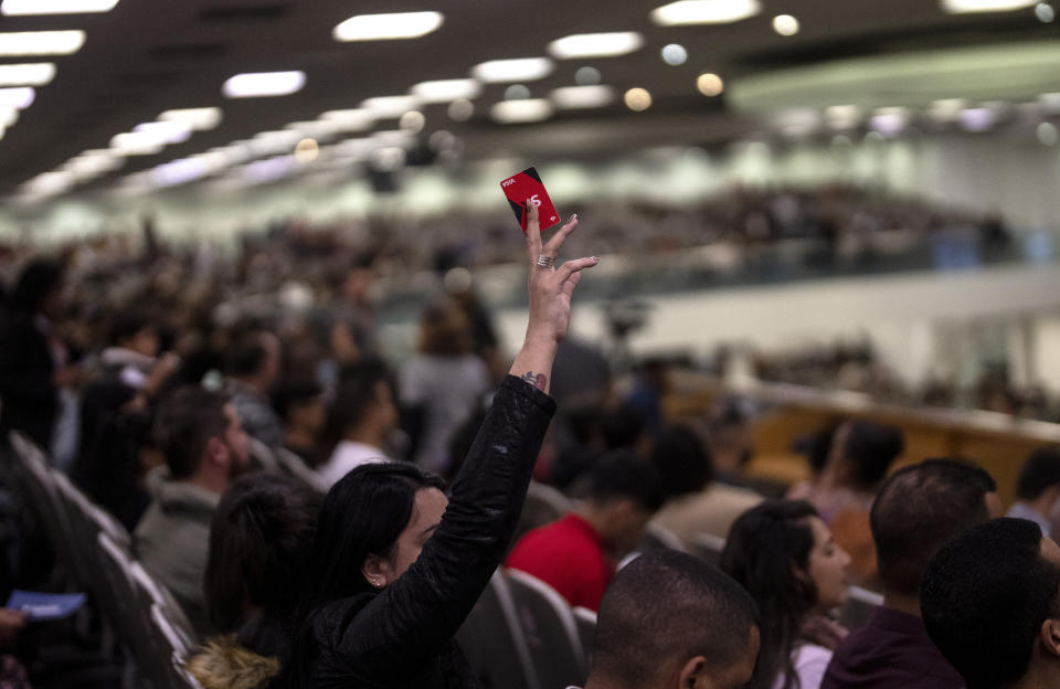 A woman holds up her credit card to summon a volunteer in order to pay her tithe during a worship service at the Assembly of God Victory in Christ pentecostal church, in Rio de Janeiro, Brazil, Sunday, Sept. 4, 2022. Evangelicals make up almost a third of Brazil’s population, more than double two decades ago, according to demographer Jose Eustaquio Diniz Alves. He projects they will approach 40% by 2032, surpassing Catholics. (AP Photo/Rodrigo Abd)